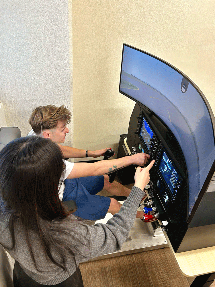 Two people practicing together at a flight simulator.
