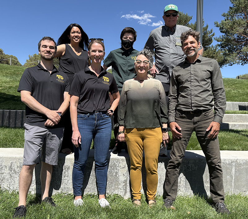 The seven staff members of the tels department standing proudly in a group outdoors: An Pfister, Max O'neil, Barrett Johnson, Nick DiPaolo, Christina Goldsmith, Cheryl Colan and Thatcher Bohrman