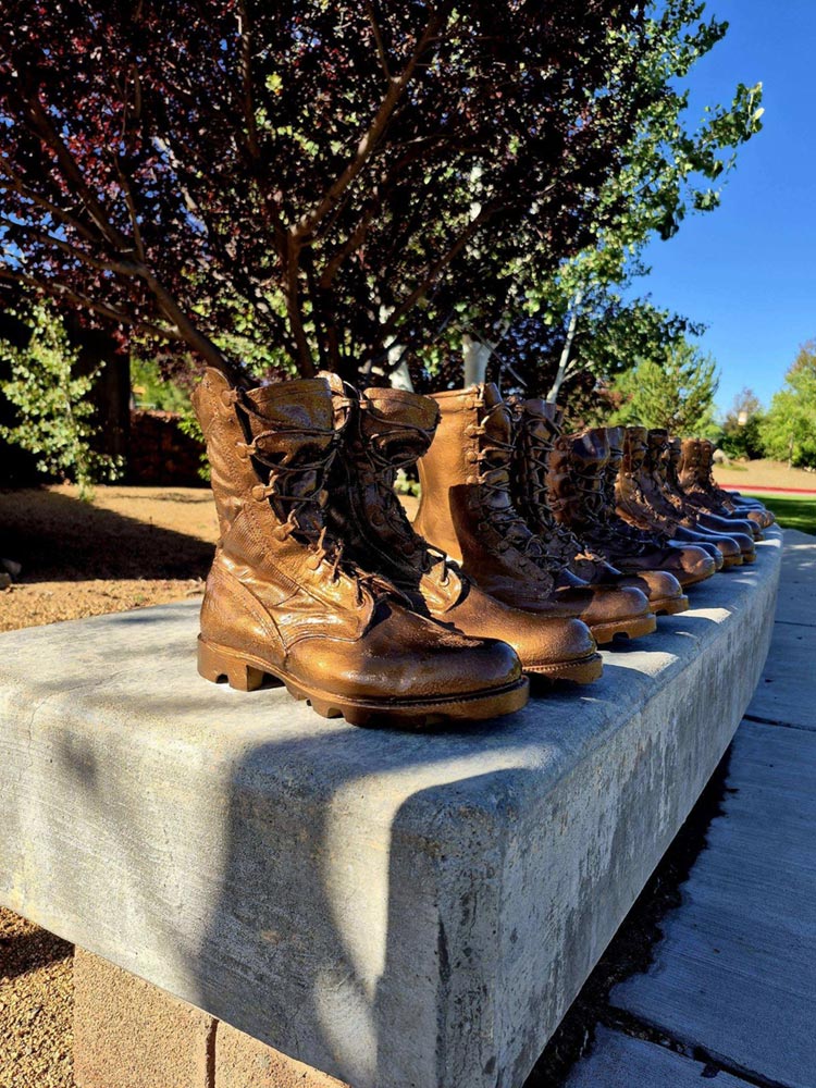 Close view of memorial boots arranged along a curved stone bench.
