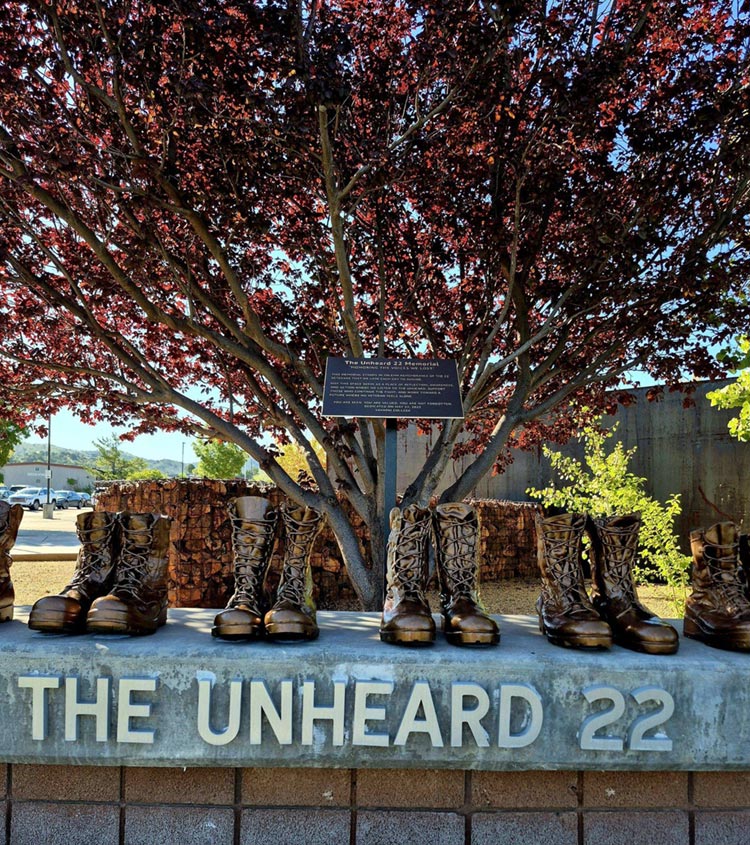 Boots beneath a tree above the inscription The Unheard 22.